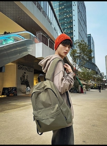 Detail of olive green nylon backpack with grid pattern and large front zipper pocket