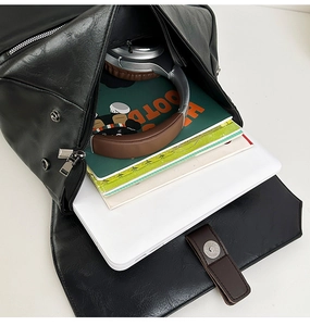Spacious interior of black leather travel backpack showing laptop and books storage