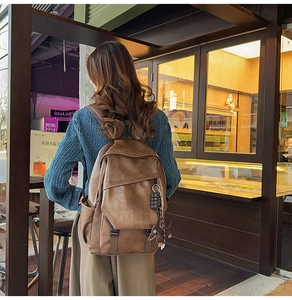 Detail of vintage brown leather backpack with flap closure and cute dog charm pendant