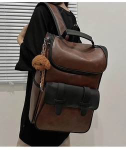 Detail of dark brown PU leather backpack with vintage buckles and plush bear pendant