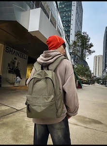 Detail of army green nylon backpack with grid pattern showing side view and zipper pocket