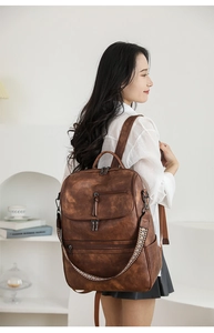 Detail of vintage brown leather backpack showing side metal rings and woven strap accents
