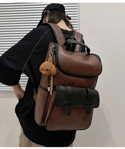 Detail of dark brown vintage PU leather backpack with buckle pocket and plush pendant