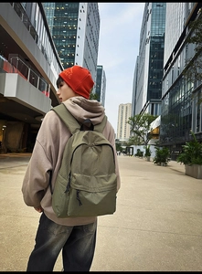 Outdoor shot of army green grid nylon backpack for women with front zipper pocket