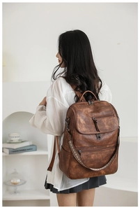 Detailed close-up of brown vintage leather backpack with woven strap and metal zippers