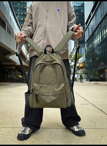 Detail of army green nylon backpack with checkered texture in urban outdoor setting