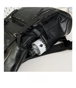 Close-up of the black pebbled leather backpack side pocket holding a water bottle
