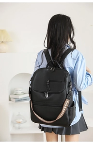 Detail of vintage black leather backpack with geometric woven strap on female model