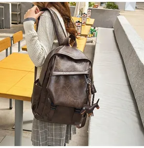 Close-up of retro brown leather backpack with buckle detail and dachshund charm