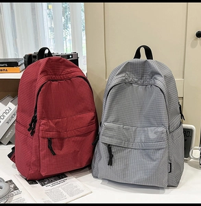 Detail view of lightweight nylon backpacks with fine grid patterns in red and grey