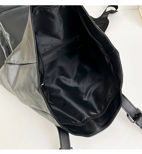 Internal view of black leather backpack showing spacious main pocket and zippered pocket