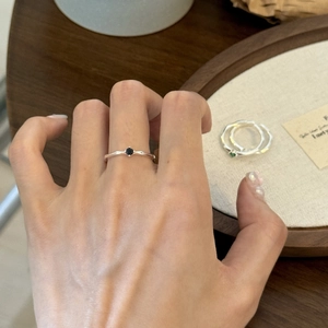 Macro detail of minimalist silver ring with black zircon stone on elegant linen display