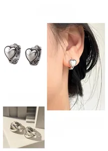 Dettaglio di orecchini a cuore in metallo vintage con bordi perlati e finitura argento