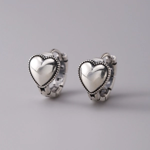 Dettaglio di orecchini a cerchio a cuore in argento S925 con bordo perlato vintage e finitura