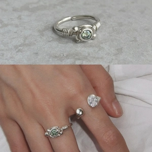 Ensemble de bagues argentées avec zircon vert et design torsadé sur main et roche