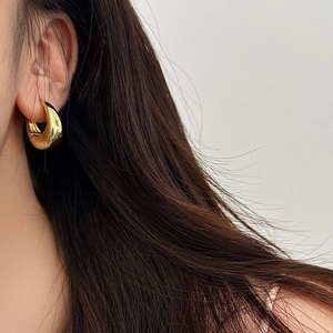 Minimalist gold-finished teardrop U-shaped hoop earrings for women on a model