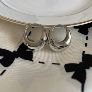 Polished silver teardrop U-shape earrings on porcelain with minimalist metal finish