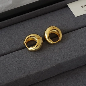 Polished gold U-shaped hoop earrings on grey velvet, minimalist chunky water drop style