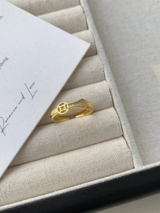 Gros plan sur une bague dorée ajourée avec pièce de monnaie et zircons blancs