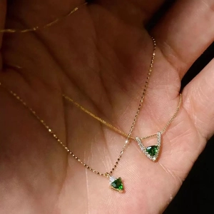 Double-layered gold necklace with triangular green zircon pendants in hand presentation