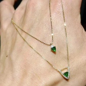 Detail of double-layer gold necklaces with triangular green zircon pendants and diamonds