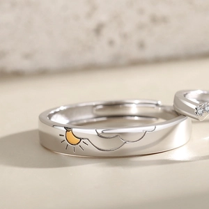 Macro view of sun and cloud engraving with gold accents on a silver band ring