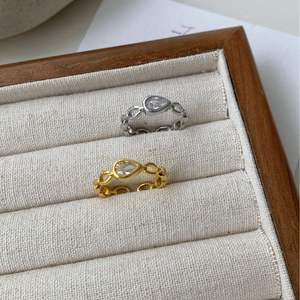 Gold and silver chain rings with pear-cut zircon stones displayed on a jewelry tray