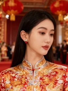 Detail of red bead earrings with golden bow knot worn with traditional embroidery