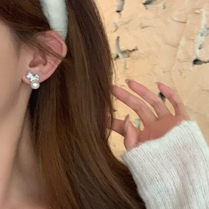 Close-up of bowknot pearl earrings in silver finish worn by a model for a chic look