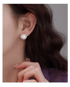 Detail of vintage silver woven metal earrings with white pearl inlay worn on ear