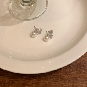 Detail view of bear stud earrings with pave setting crystals and round white pearls