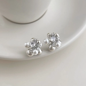 Elegant silver flower stud earrings with white pearls and zircon on ceramic tray