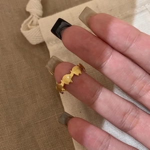 Dettaglio dell'anello ondulato in oro opaco con piccoli diamanti al dito con sacchetto
