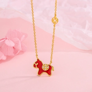 Collier doré avec pendentif cheval en émail rouge et breloques de pièces sur fond rose