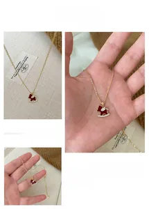 Gros plan du pendentif cheval rouge avec zircons incrustés et chaîne dorée fine