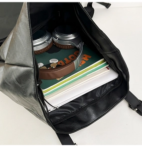 Top view of spacious black leather backpack interior with laptop and headphones