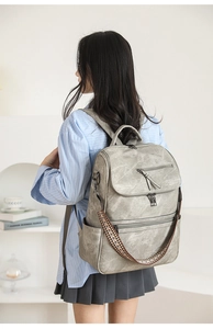 Detail view of vintage grey backpack featuring chic ethnic rainbow strap on model