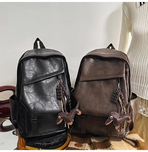 Detail of vintage leather backpack with chocolate and dachshund pendants in black and brown