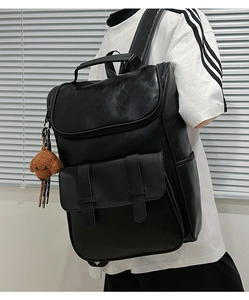 Side view of black PU leather backpack with magnetic buckles and a brown puppy charm