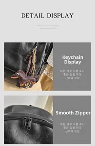Detail view of smooth dual metal zippers and a brown dachshund leather pendant on black bag