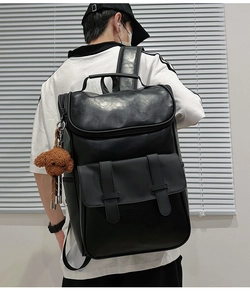 Detailed back view of a black PU leather backpack featuring metal buckles and a teddy bear charm
