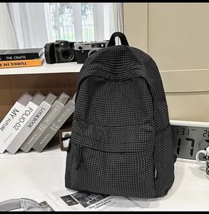 Detail of black and white checkered backpack with front pocket and side woven brand label