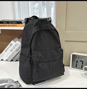 Close-up of black and white checkered backpack with front zipper pocket and side water bottle pouch