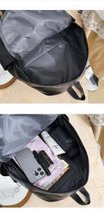 Detail view showing large capacity interior of black leather backpack with daily essentials
