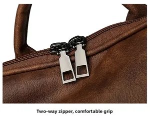 Macro detail of brown pebbled leather texture with sturdy dual metal zippers and top handle
