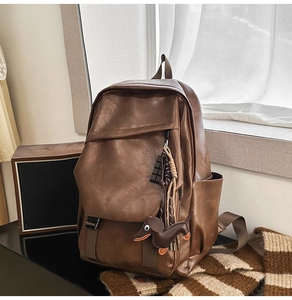 Brown leather backpack detail featuring flap closure and cute dachshund dog charm