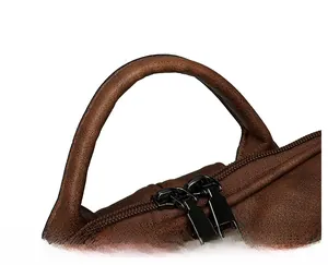 Detail of reinforced faux leather handle and dual metal zippers on vintage brown backpack