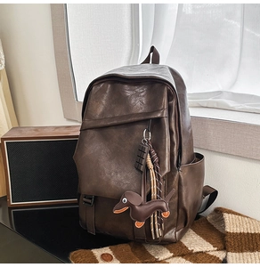 Detail of dark brown leather backpack with playful charms in a vintage retro setting
