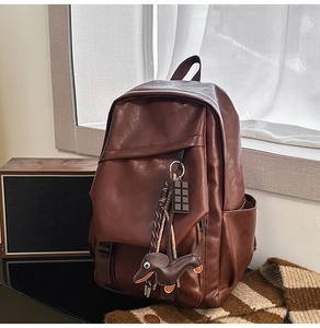 Detail of dark brown leather backpack with cute dachshund dog and chocolate bar pendants