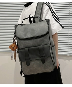 Side view of matte gray PU backpack featuring black buckle straps and cute bear pendant